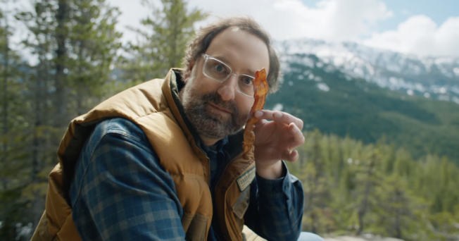 Man holding a bacon strip in the woods