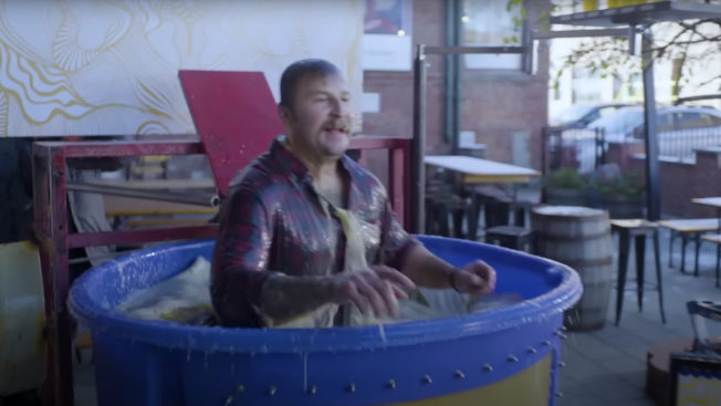 A man splashes into a blue plastic dunk tank filled with beer