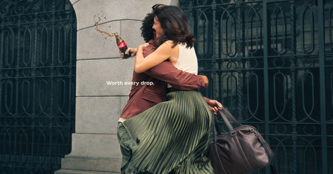 Two people embrace while spilling a Coke.